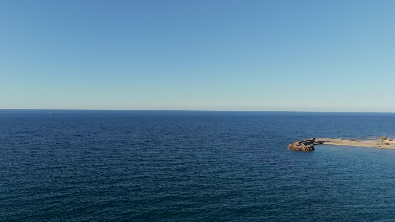 Aerial view of calm blue waters meeting the rocky shoreline in Crete, Greece