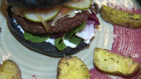black bun vegan burger with potato wedges