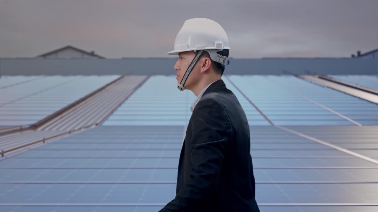 Side View of Asian Businessman Walking, Checking Time in Watch at Industrial Rooftop Solar Panels