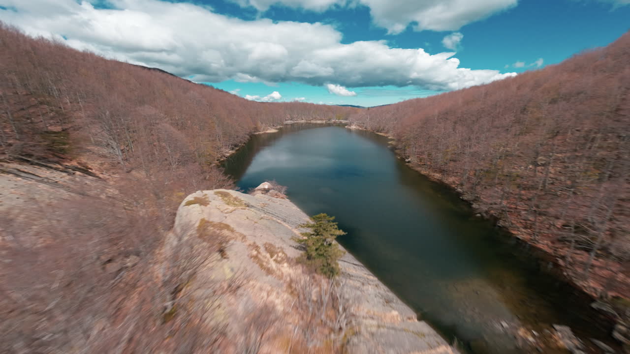 Aerial view over leafless forest valley with lakes and dramatic cloudy sky