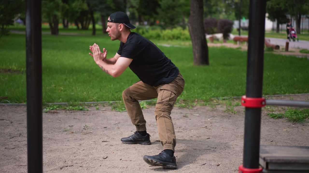 Male Individual Testing Strength At Outdoor Park, Person Engaged In Precise Squat Training In Open Air, Male Participant Practicing Careful Lower Body Workouts Amidst Natural Outdoor Surroundings