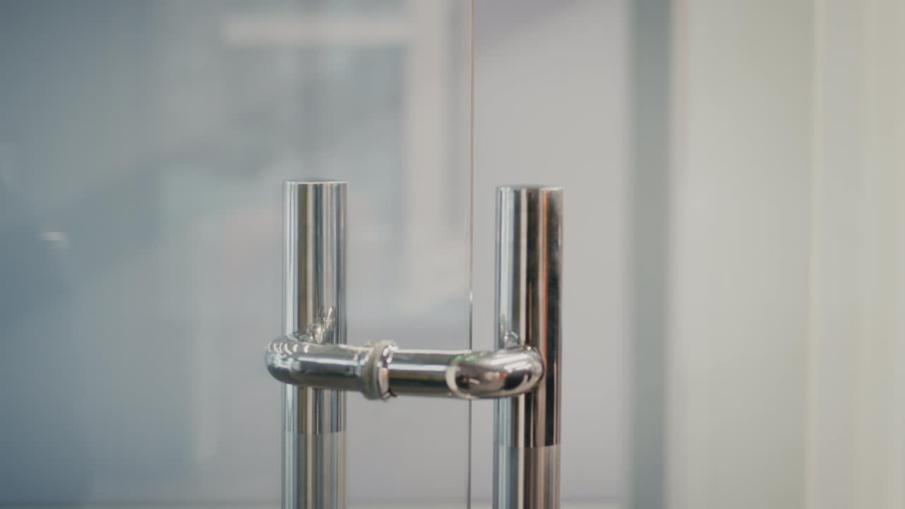 hombre irreconocible entrando en la oficina abriendo la puerta de vidrio en el interior, recortado