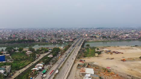 Centro-Compacto-Con-Autos-Cruzando-El-Puente-De-La-Carretera-Sobre-El-Río-Taguig-En-La-Ciudad-De-Taguig,-Metro-Manila,-Filipinas