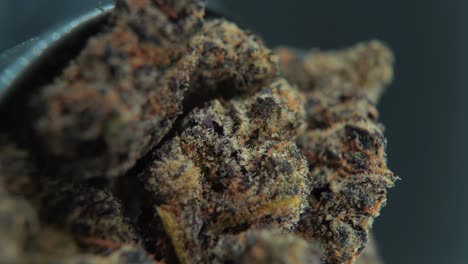 una toma cinematográfica macro vertical detallada de una planta de cannabis, variedades híbridas de naranja, indica y sativa, flor de marihuana negra, en un soporte giratorio, cámara lenta, video 4k, iluminación de estudio