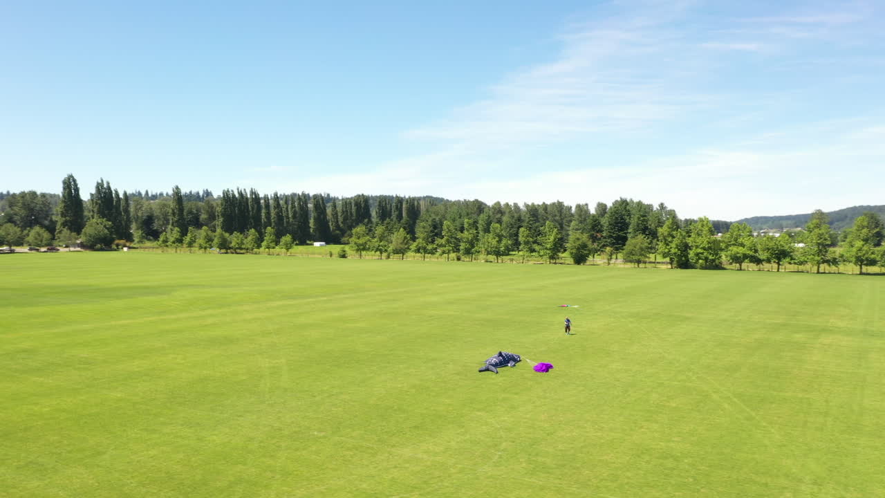 Aerial Orbit around Man walking towards giant kite in the middle of the park