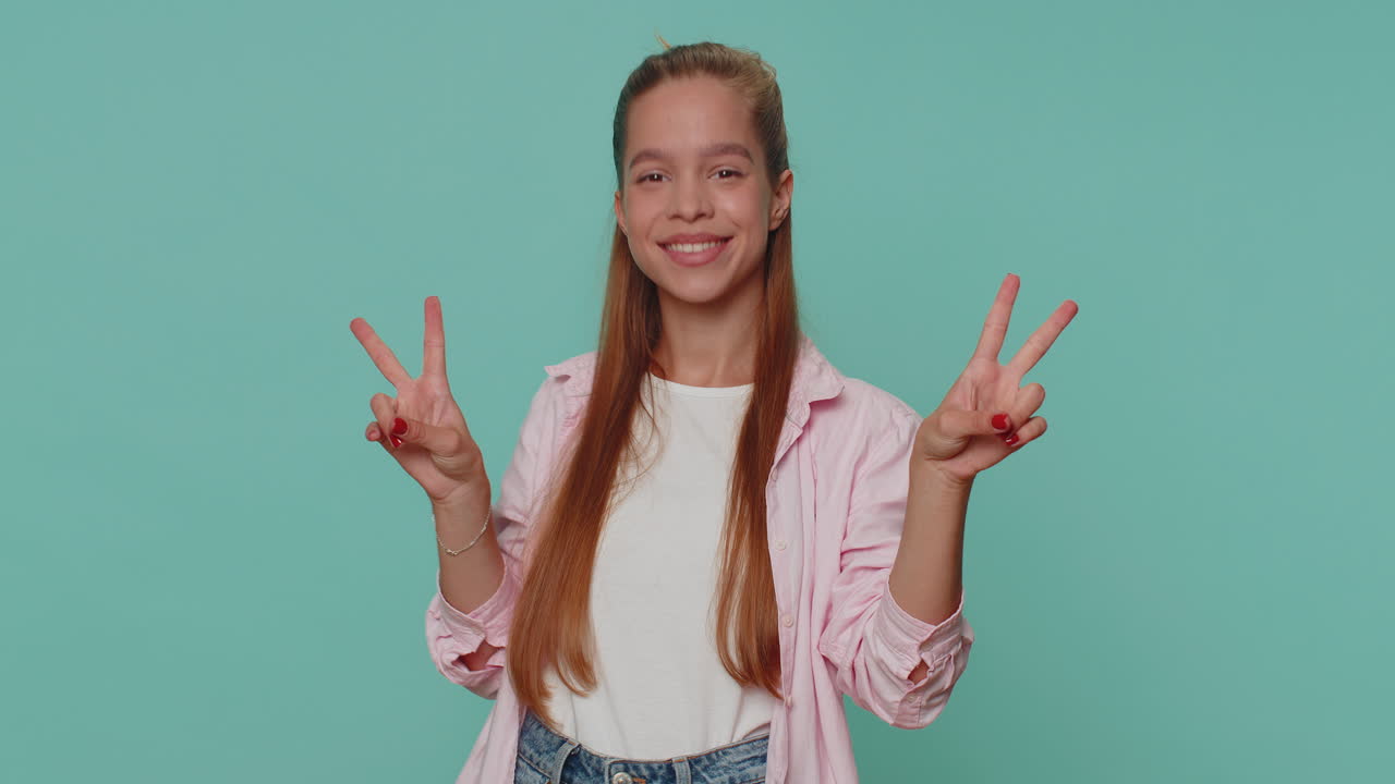 bella ragazza felice bambino che mostra il segno della vittoria, sperando nel successo e nella vittoria, facendo un gesto di pace, sorridendo