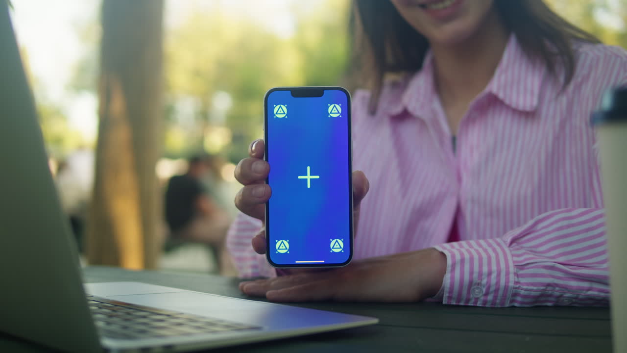 Woman hand holding phone with chroma key screen outdoor. Smartphone with green screen close-up
