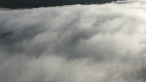 dron volando por encima de las nubes inclinándose para revelar la cumbre de la montaña