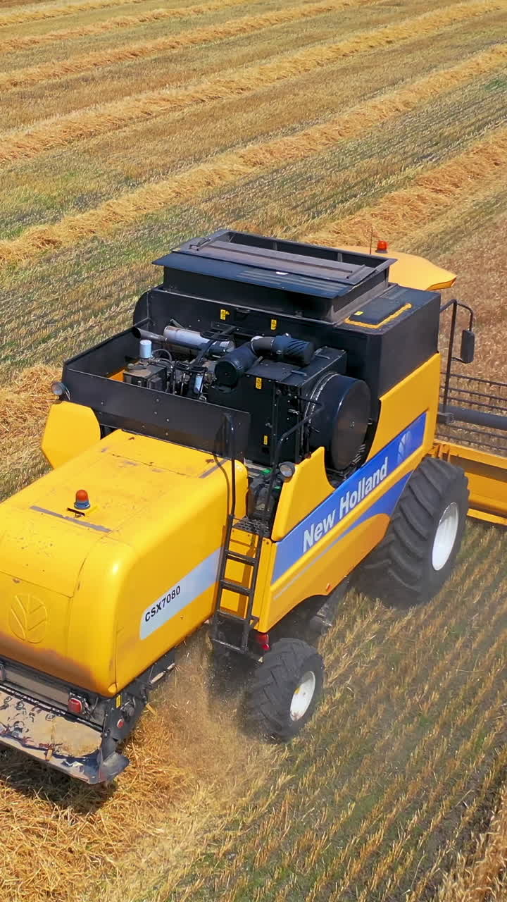Aerial landscape of agriculture. Aerial view of several harvesters on field of wheat. Vertical video
