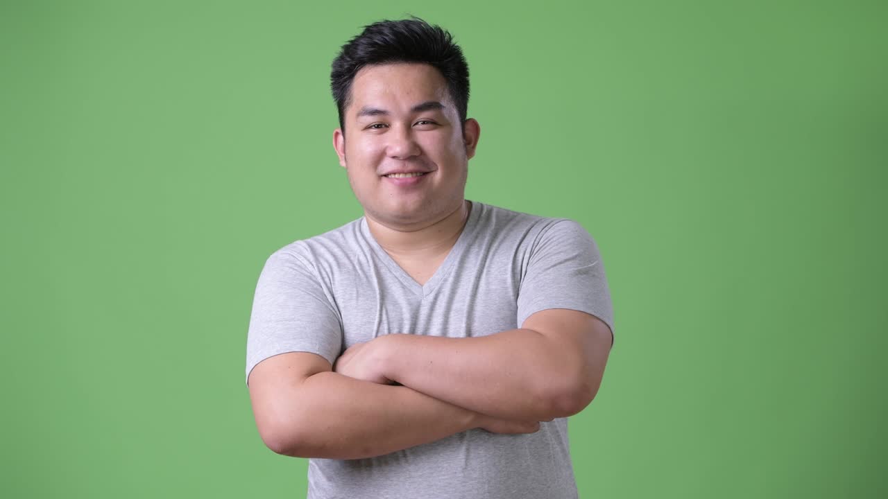 초록색 배경에 젊은 잘생긴 과체중 아시아인