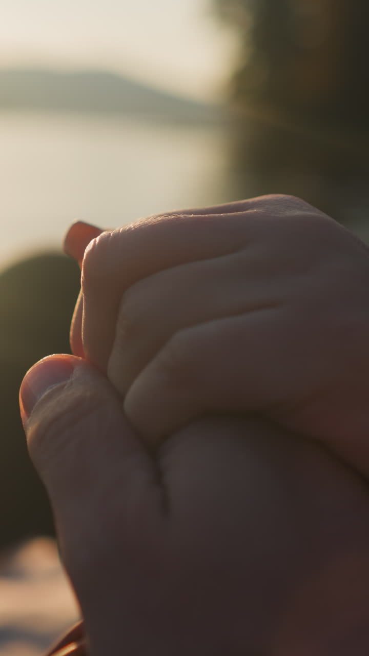 해가 지는 곳에서 손을 잡고 앉아 있는 연인들: 남자친구가 강변에서 여자친구와 함께 데이트의 만적인 분위기를 즐긴다.