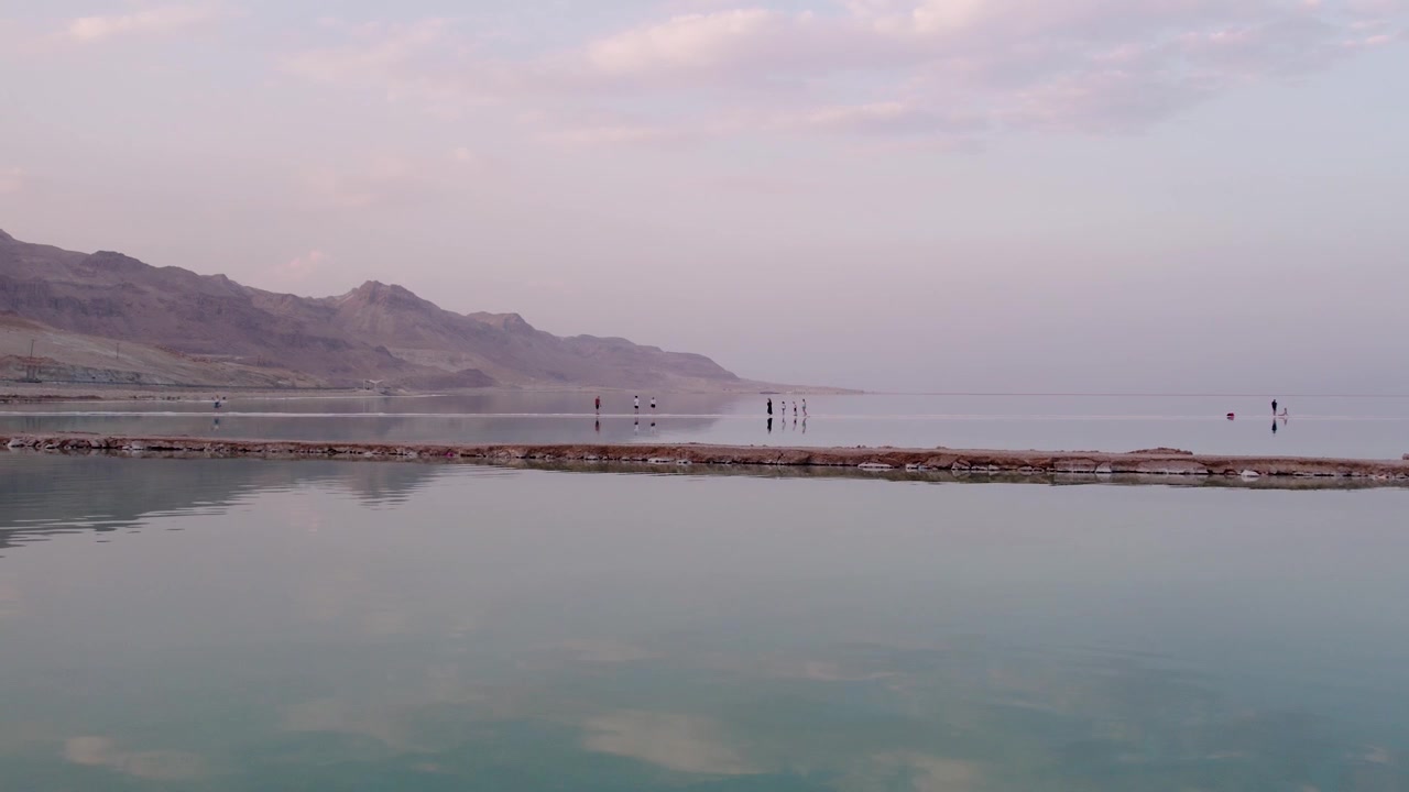 Persone che camminano su una formazione di sale nel calmo Mar Morto.
