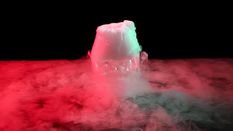 cognac glass with the effect of white smoke dry ice at black background with red light. slow motion - cognac glass with the effect of white smoke dry ice at black background with red light at studio, chemical reaction with smoke on dark surface. slow motion
