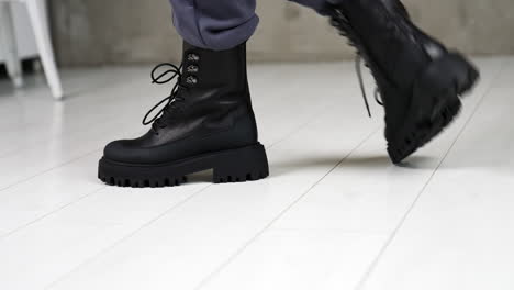 model demonstrating the fashionable black leather boots with laces. footwear presentation in light studio. close up.