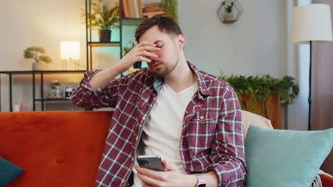 shocked sad man using smartphone reading negative e-mail message feels annoyed app virus crash