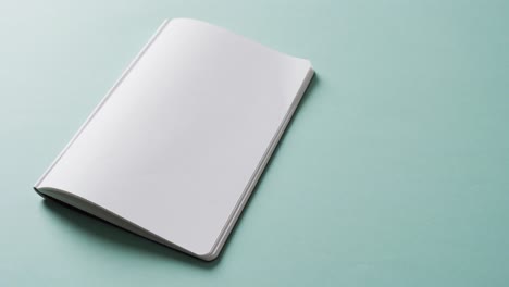 close up of open blank book with copy space on green background in slow motion