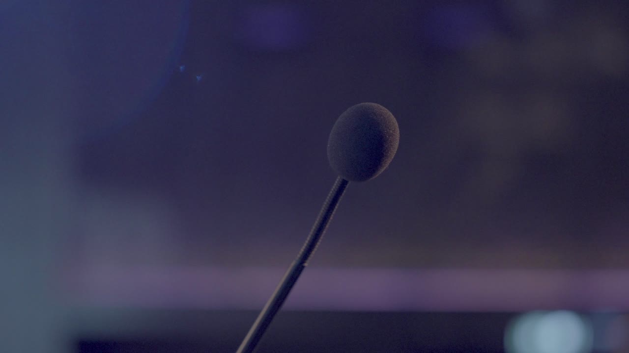 A close-up of the microphone on stage, ready for the speaker to share their message at the event