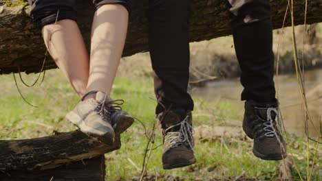 couple sitting on tree trunk with feet dangling, taking a break during hike