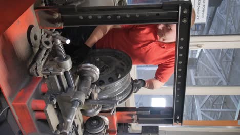man repairing a car wheel rim on a specialized machine in a workshop
