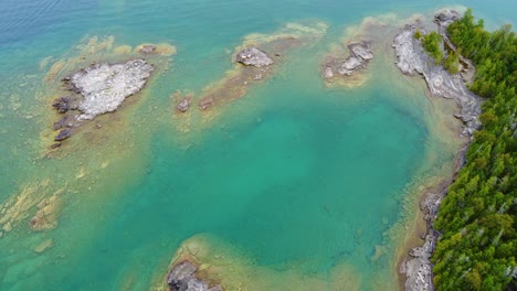 Rocky-coast-with-lush-pine-trees-and-calm-water-in-Georgian-Bay-Aerial-tilt-down-shot