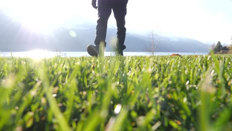 male hiker walking towards camera on grass beside lake in walenstadt, switzerland