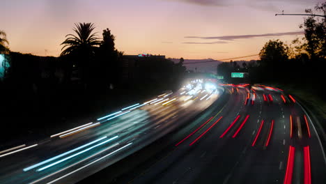 lapso de tiempo del tráfico de autopista ocupado con desenfoque de movimiento en los ángeles al atardecer