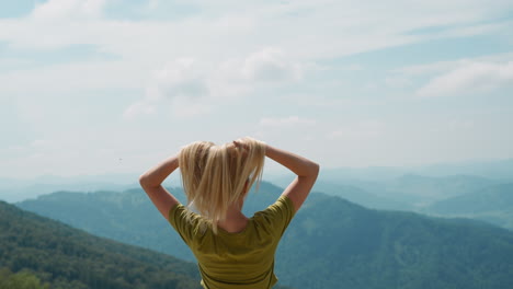 graceful tourist puts hands up against mountainous valley