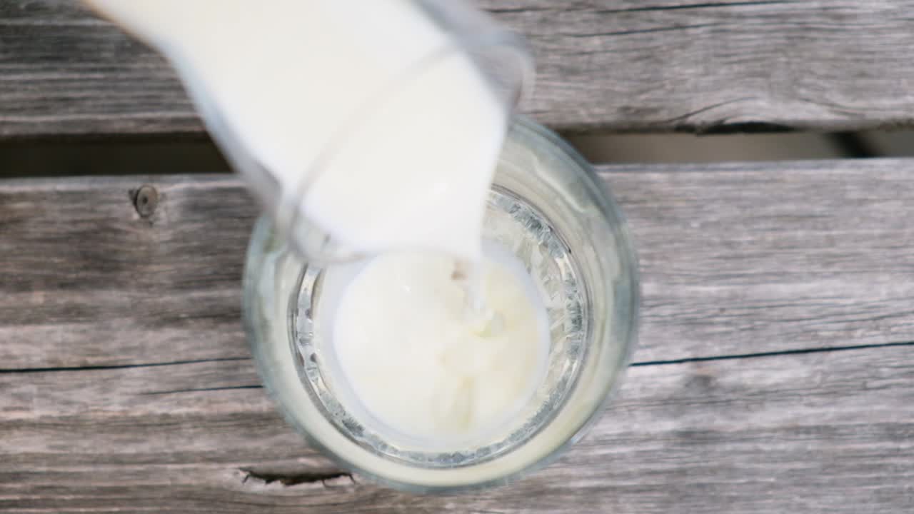 vertiendo leche en un vaso en los alpes en una montaña, fresca de las vacas ubicación: tirol del sur, italia