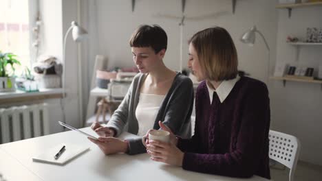 Two-woman-students-using-tablet-computer-for-online-education-in-home