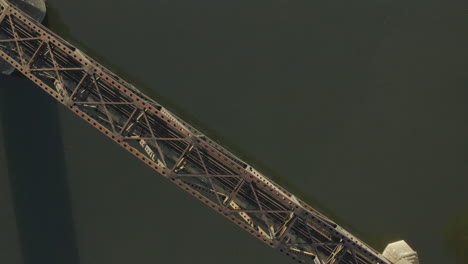 orbiting overhead drone shot of steel rail bridge over a river shot at sunrise