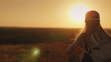 a carefree child with a knapsack behind him runs towards the sun summer holidays and freedom concept