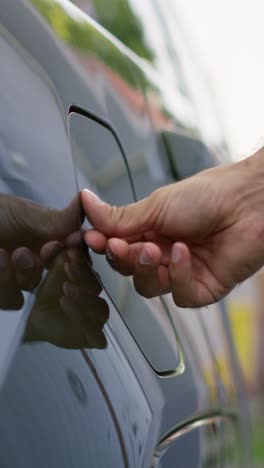 vertical video close up of driver opening electric vehicle charging port flap to charge battery