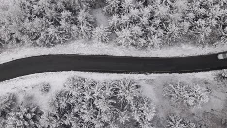 car driving along an empty road through a beautiful, snow covered forest in the stunning countryside of west germany