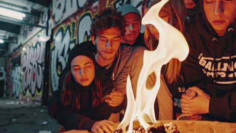 two young people looking at something in a graffiti-covered urban environment at night