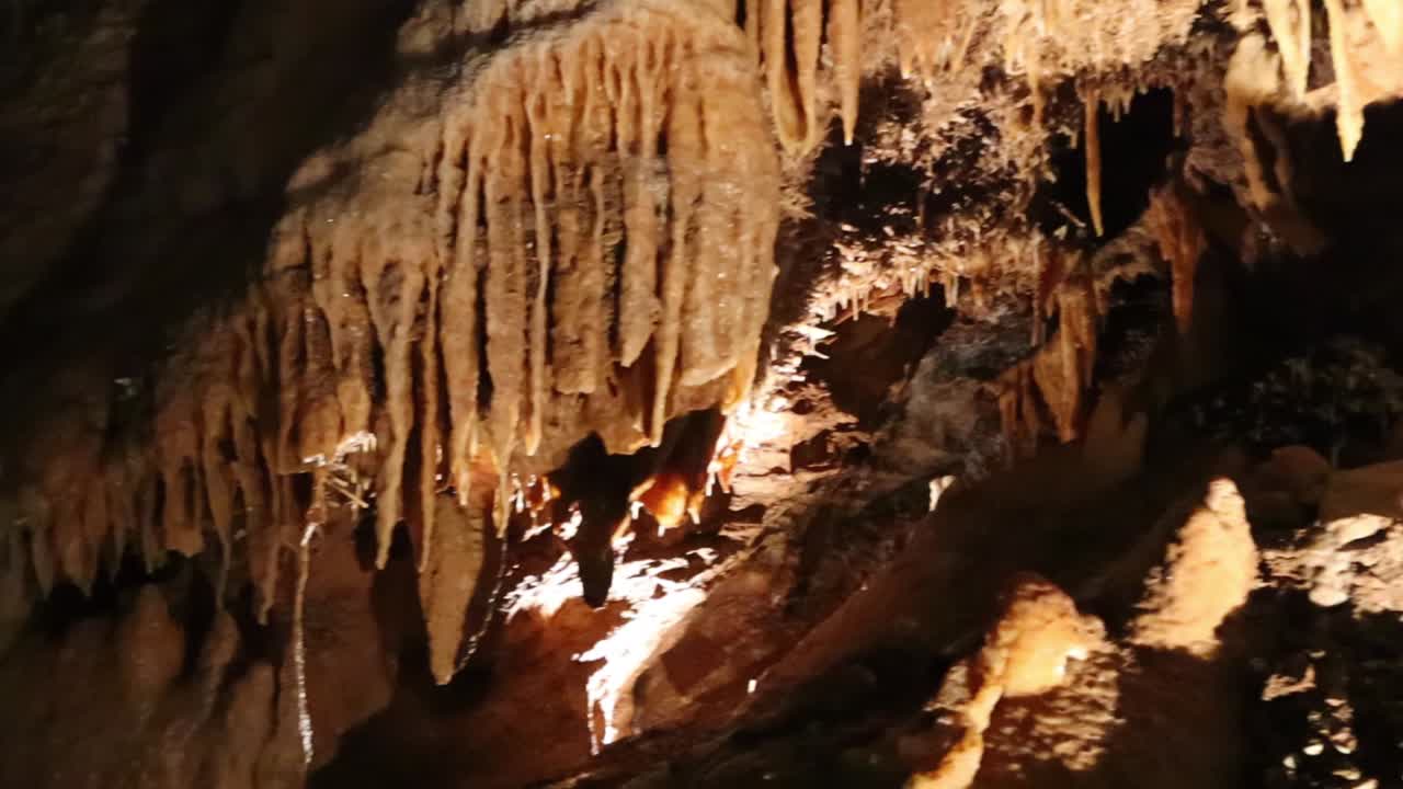 Handheld pan right shot of stalactites in cavern at Jenolan Caves, NSW