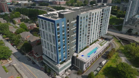 aerial slide and pan footage of luxurious multistorey apartment building with terrace and swimming pool