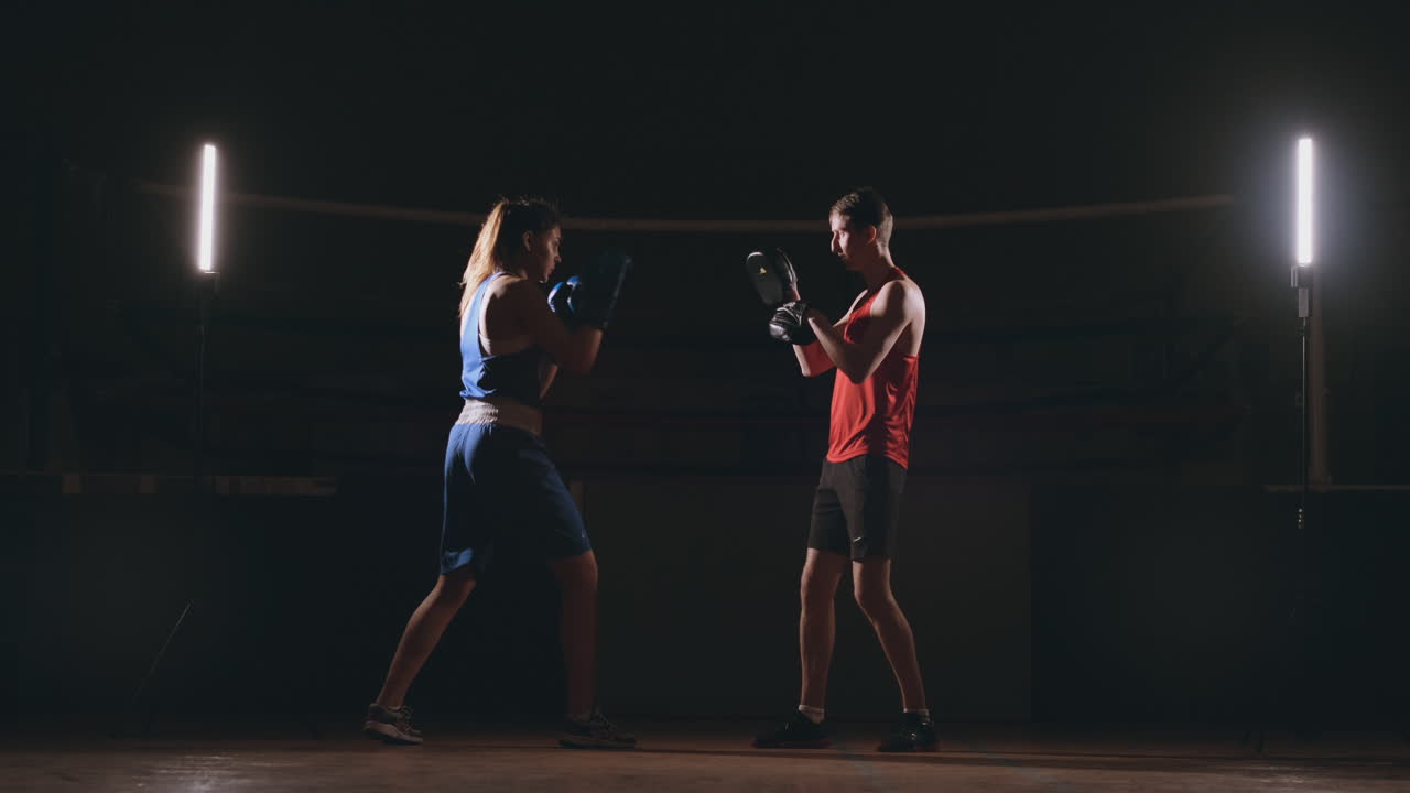 Young adult woman doing kickboxing training with her coach.
