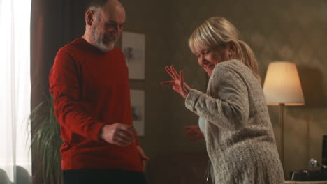 happy elderly couple dancing at home