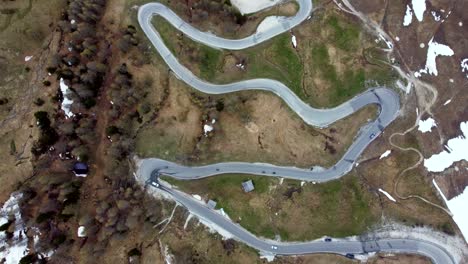 top down view of a curved alpine road on which vehicles are passing through in the italian dolomites