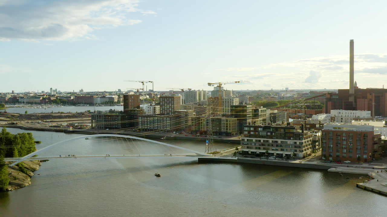 Ripresa aerea in salita con drone che domina il ponte Isoisansilta, il quartiere di Kalasatama e le gru che costruiscono nuovi edifici residenziali nei distretti di Sompasaari, in una giornata di sole, a Helsinki, Uusimaa, Finlandia.