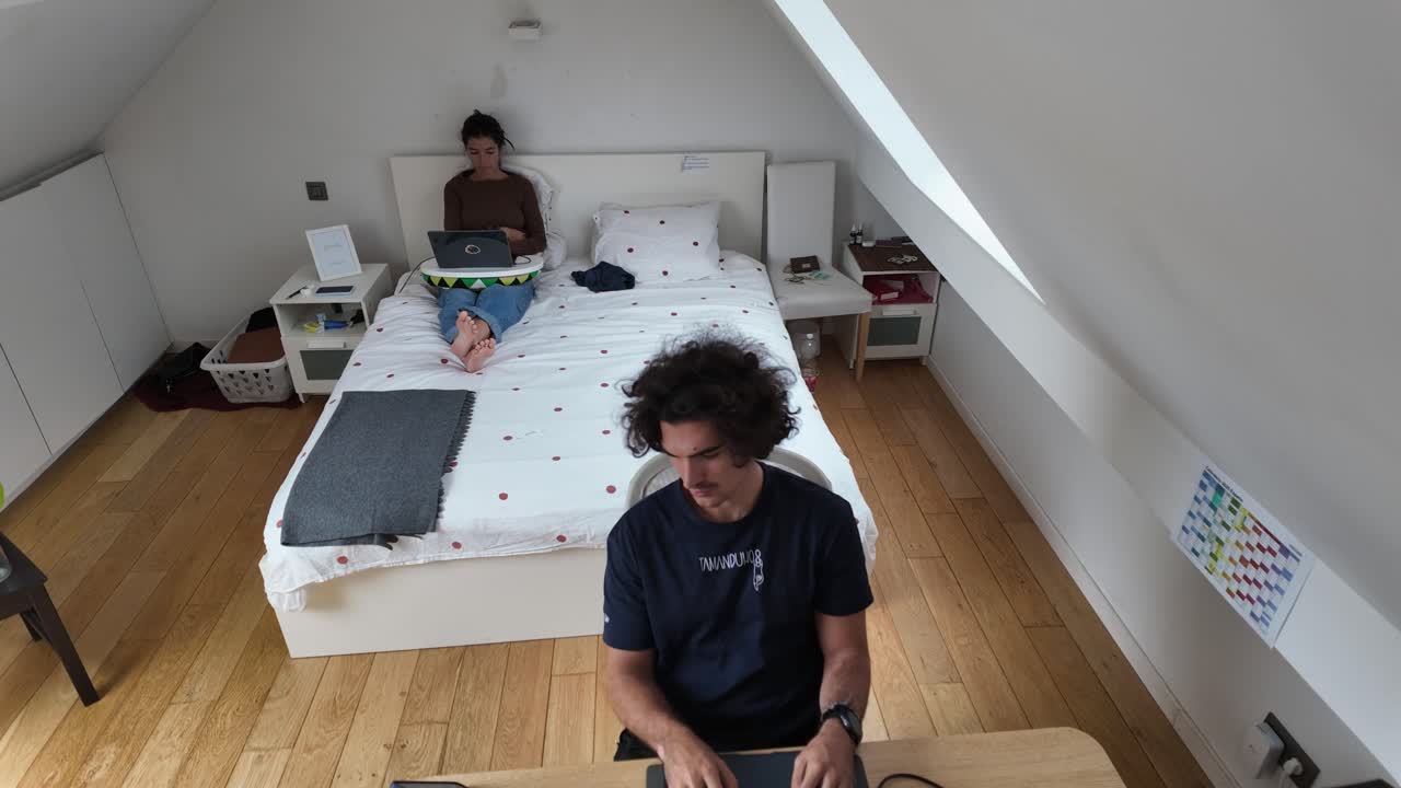 Timelapse of couple working remotely in modern attic bedroom home office