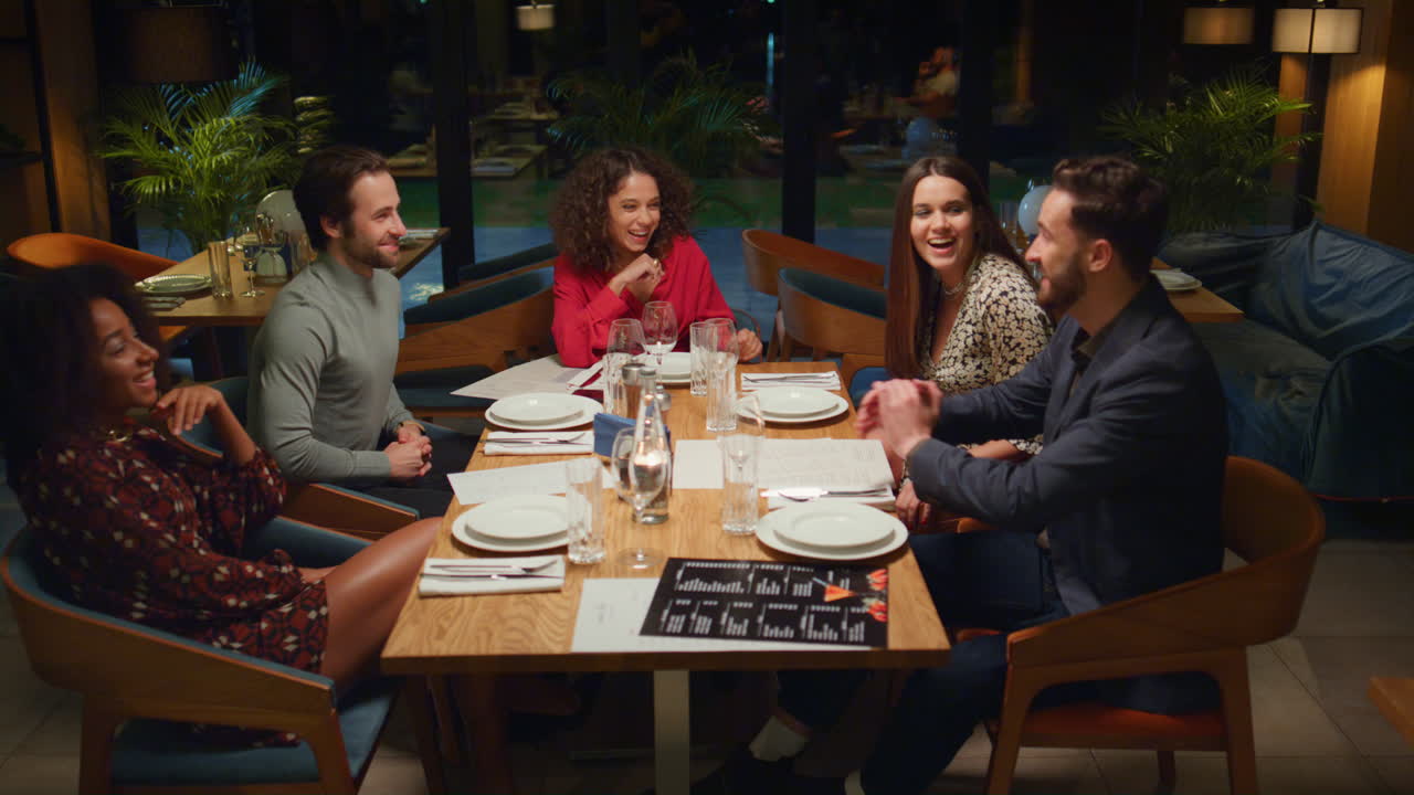 Young people having fun in restaurant. Mixed race friends enjoy evening in cafe.