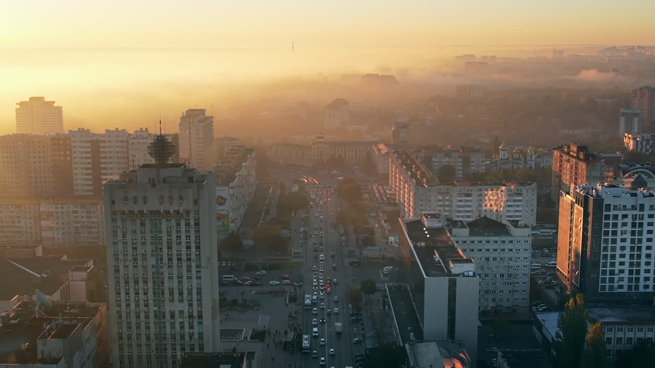 Letecký pohled dronem na Kišiněv při východu slunce, Moldavsko. Pohled na centrum města pokryté mlhou, množství budov a aut.