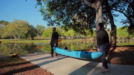 a couple preparing to kayak by a serene lake