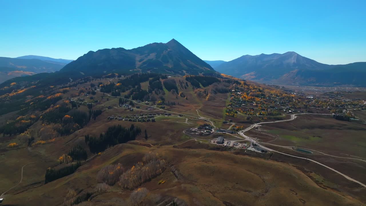Mount Crested Butte Gothic mountain town ski resort vibrant aspen trees fall autumn peak colors aerial drone Colorado morning Kebler Pass Gunnison National forest sunny morning blue sky forward pan up