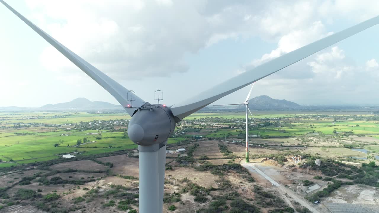Aerial close up drone footage of wind turbine tower with rotating  propeller generating renewable power. Green energy concept to reduce global warming and climate change.