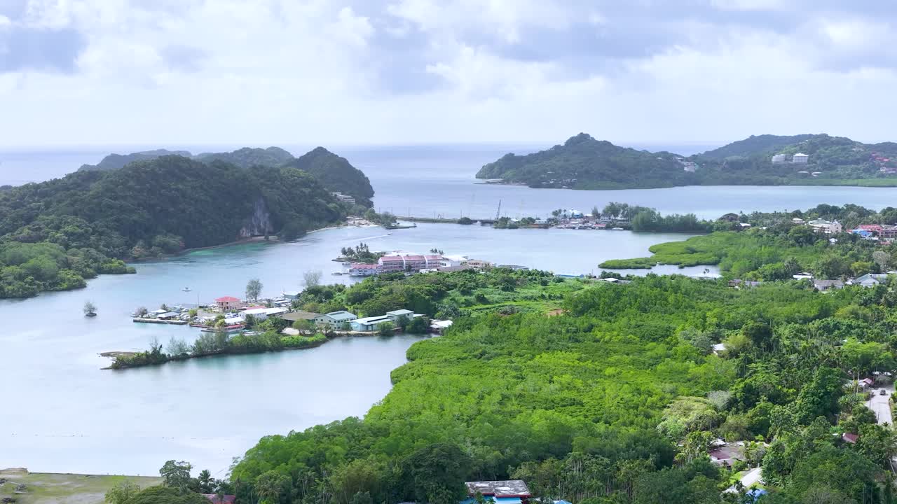 ภาพถ่ายจากโดรนมุมสูงเผยให้เห็นน้ำทะเลสีเขียวอมฟ้า เกาะสีเขียว และชุมชนชายฝั่งภายใต้แสงแดดจ้า