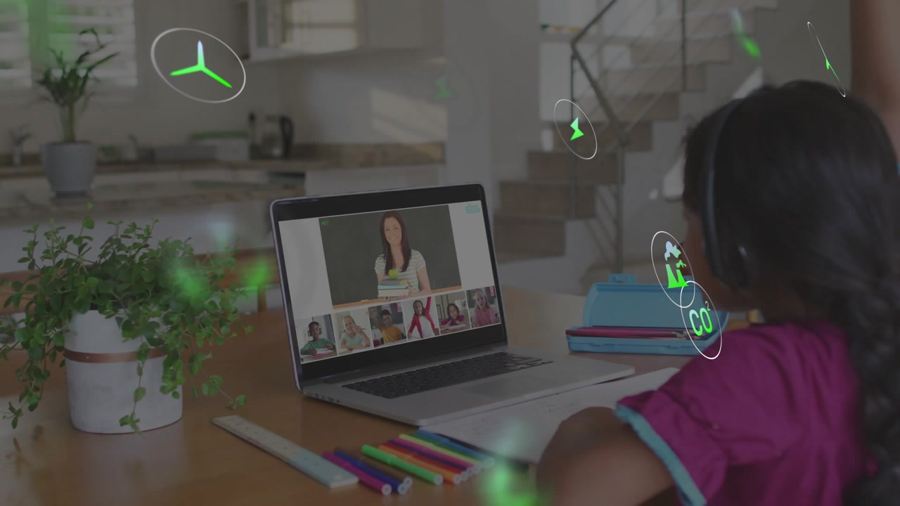 Child watching laptop and lifting arm at table as teacher leading green lesson icons orbiting desk