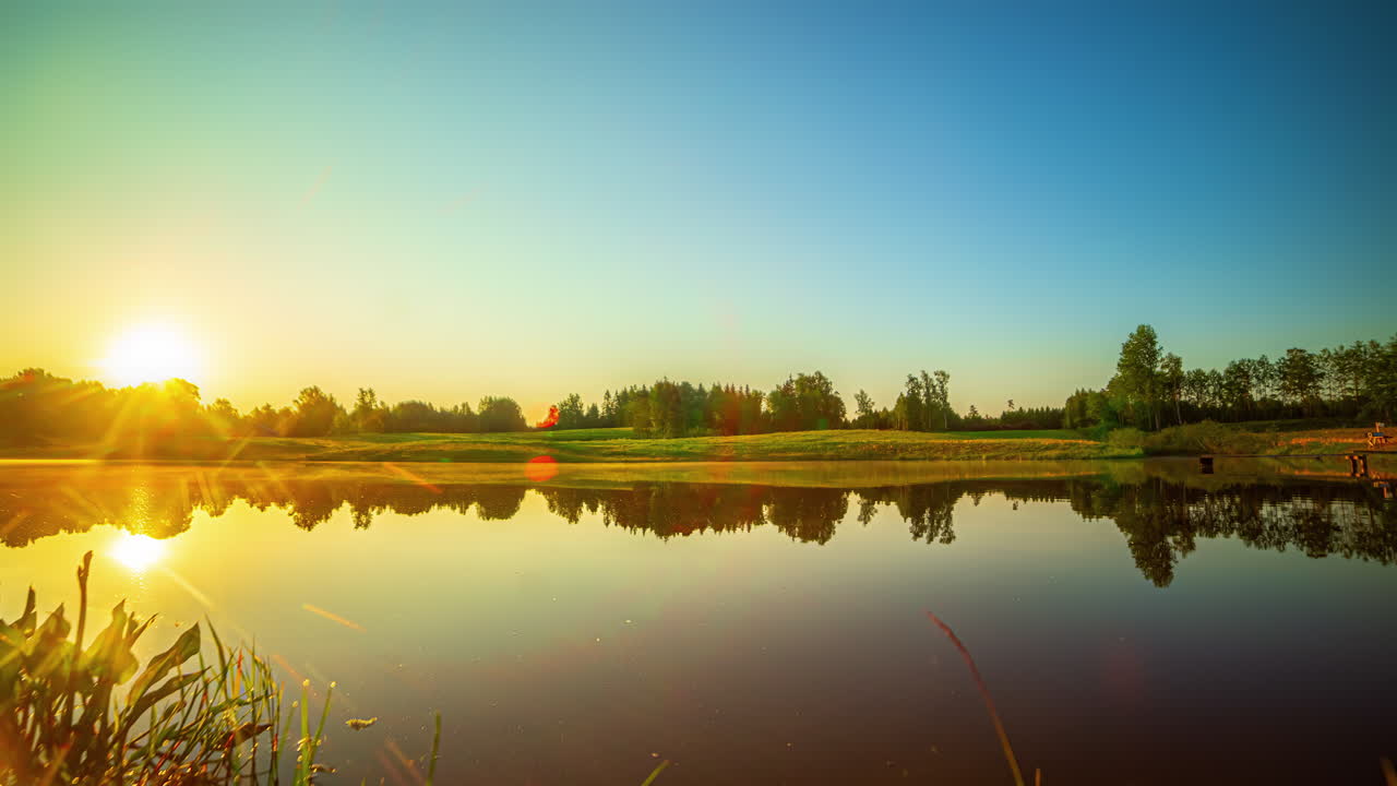 그림 같은 태양 이 호수 의 평화로운 표면 에 반사 되어 있는 것 을 보여 주는 타임  ⁇ 스, 풍요로운 초록색 의 배경 에 더욱 강조 되어 있는 것