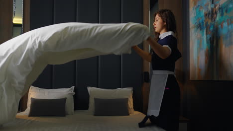 una criada haciendo una cama en una habitación de hotel